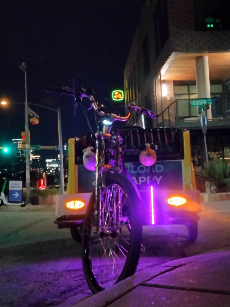 A pedicab parked under a John Deere logo.