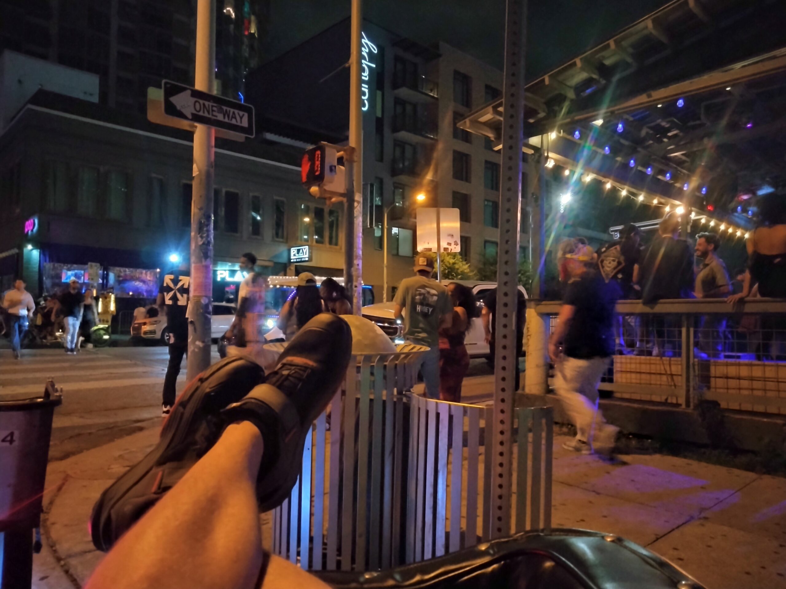 Feet up in the air on the corner of a cab, while people walk on West 6th street